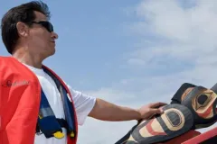 Master carver Douglas Chilton rides in the Raven Spirit canoe at its ceremonial launch.