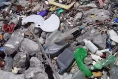 Plastic bottles and other marine debris cover a rocky beach in Curacao.