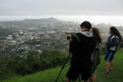 Students studying rainfall point their camera to the clouds.