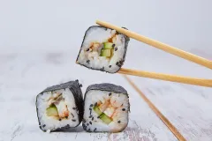 three pieces of sushi with chopsticks