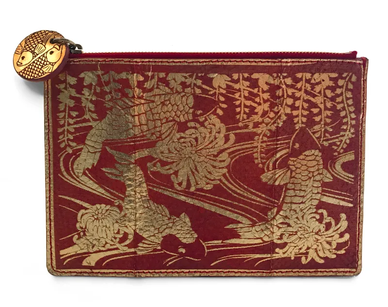 A bright red clutch bag made from fish leather and patterned with shimmering gold koi fish imagery.