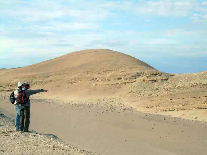 Two researchers, looking for fossil whales, scan a rock formation in Peru's Pisco Basin.